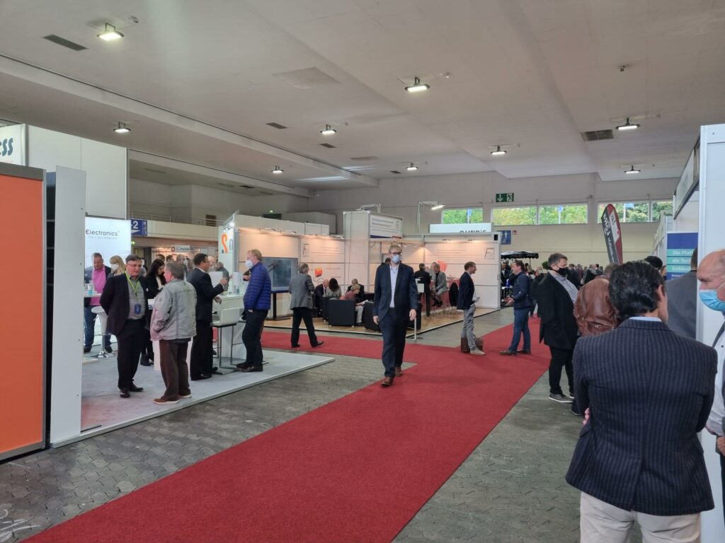 Besucher auf einer geschäftigen Messe mit roten Teppichen